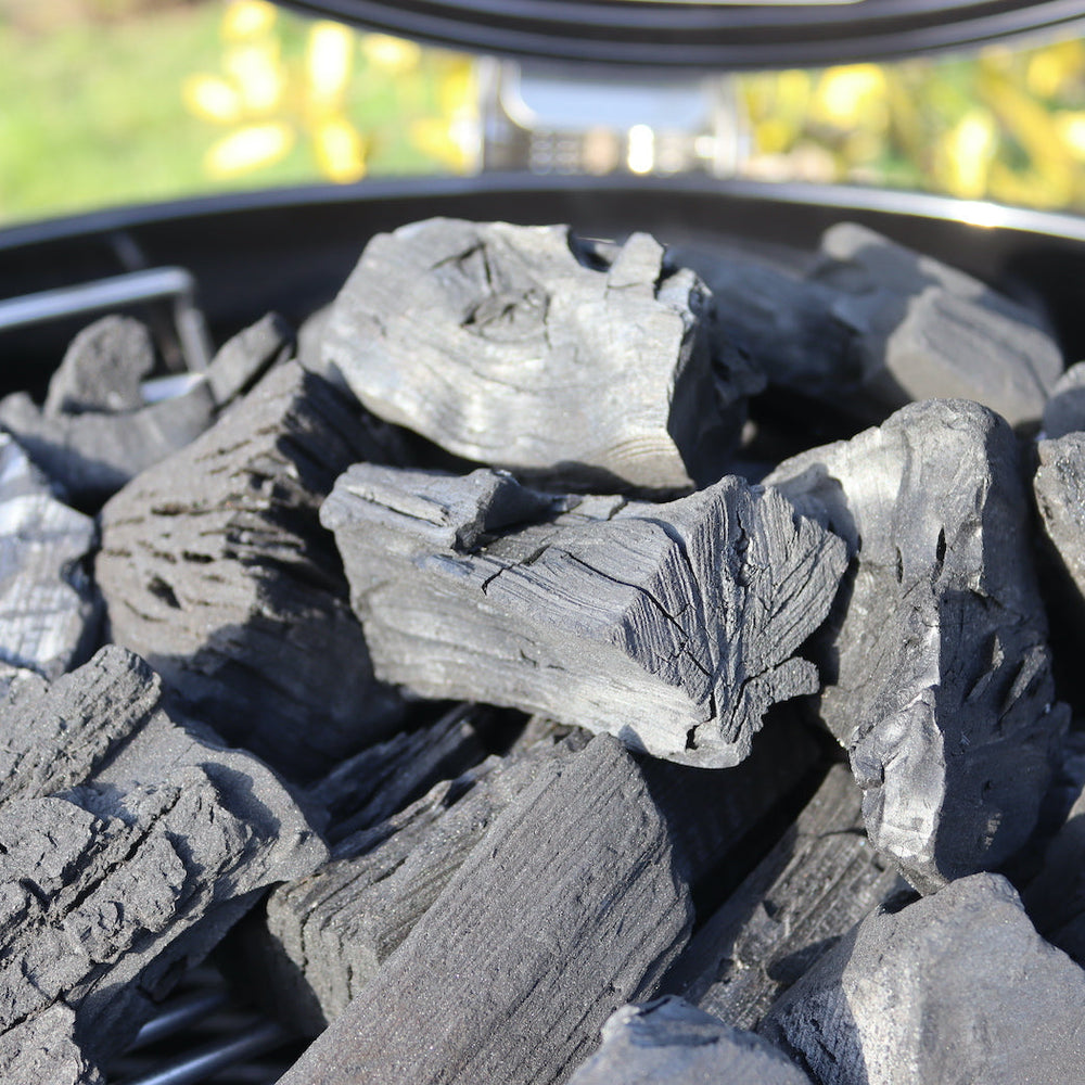 A pile of un-lit lumpwood charcoal on a BBQ