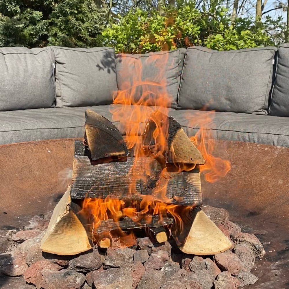 Fire pit with blazing fire next to an outdoor sofa