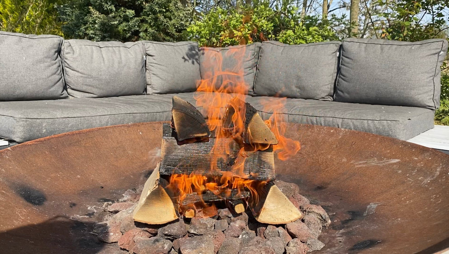 Fire pit with blazing fire next to an outdoor sofa