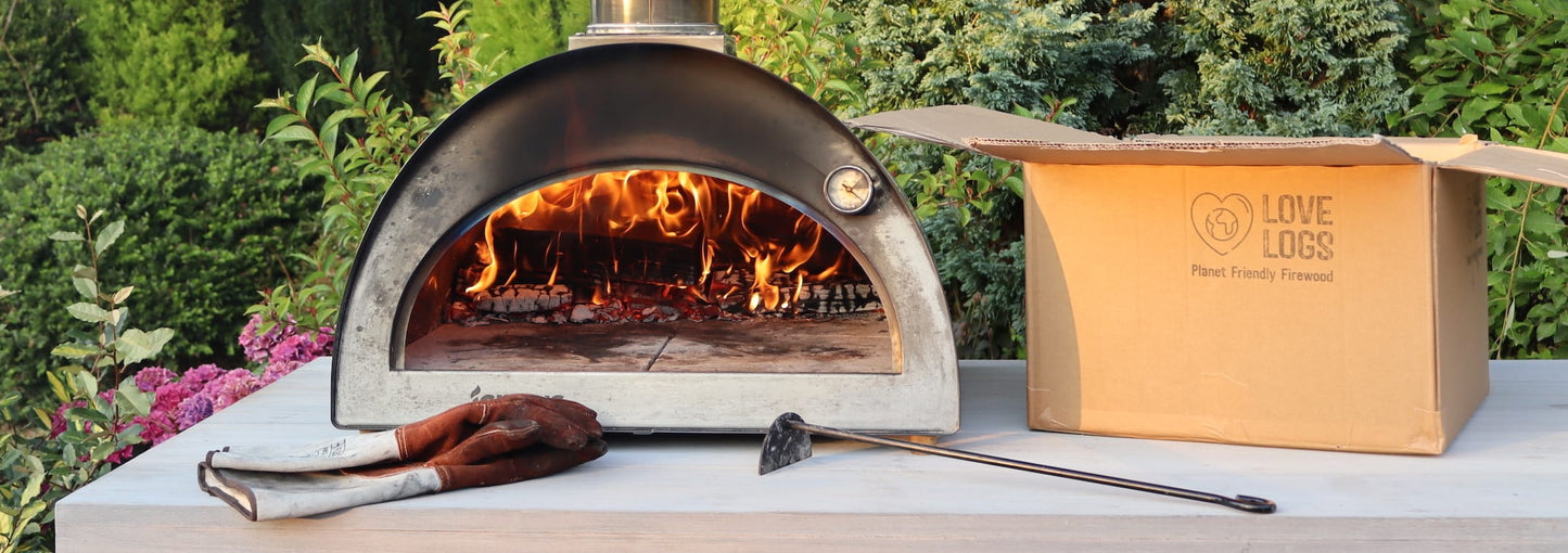 Igneus pizza oven with a roaring fire inside, next to a Love Logs box