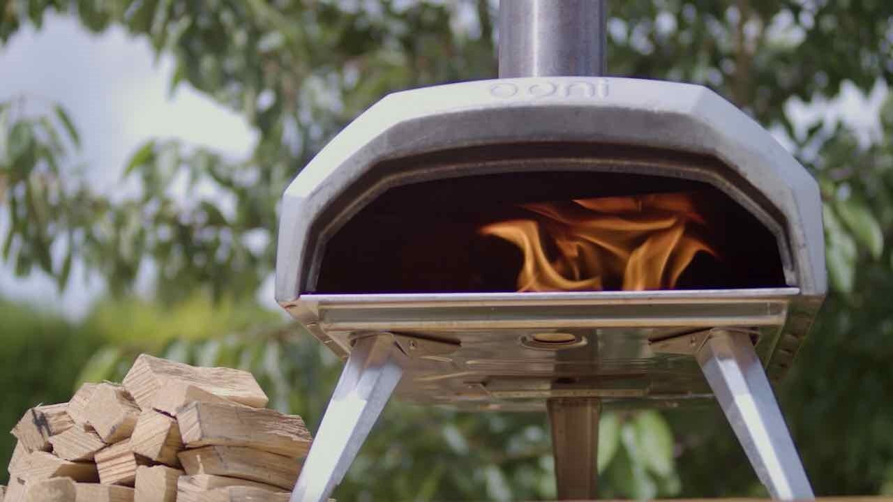 An Ooni Karu Pizza Oven next to some Love Logs hardwood kindling